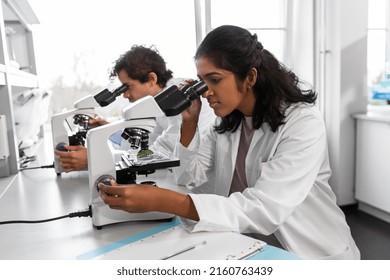 science research, work and people concept - international team of scientists with microscopes working in laboratory - Powered by Shutterstock