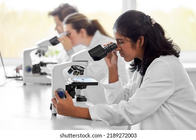 science research, work and people concept - international team of scientists with microscopes working in laboratory - Powered by Shutterstock