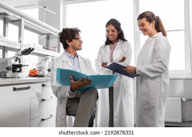 science research, work and people concept - international group of happy scientists with folder discussing report in laboratory - Powered by Shutterstock