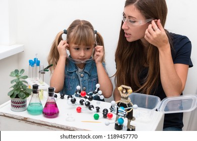 Science School, Museum Of Science. A Woman Teacher And Girl Child Collect Molecules And Conduct Chemical Experiments. On The Table Is A Robot. STEM Education.