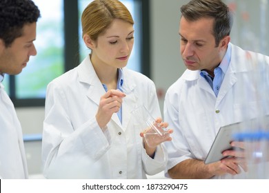 Science Student Holding Beaker Supervised By Professor