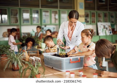 Science teacher assisting schoolgirl in planting seedlings during botany class at school. - Powered by Shutterstock