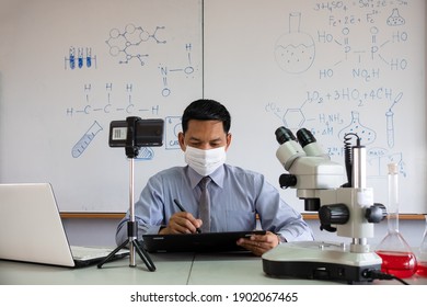 Science Teacher Wearing Mask And   Teaching Online With Smartphone In The Classroom