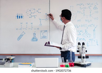 Science Teacher Wearing Mask And   Teaching In The Classroom