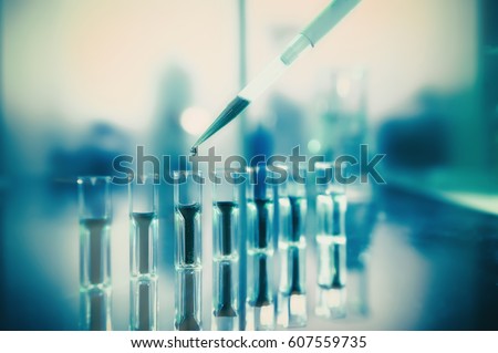 Scientific background, protein analysis. Spectrophotometer quvettes on a reflective surface, copy space. Focus on the pipette tip. This image is toned.