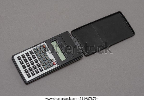 Scientific calculator against gray background.\
Rectangular device designed for engineering and scientific clock\
calculations. Selective\
focus.