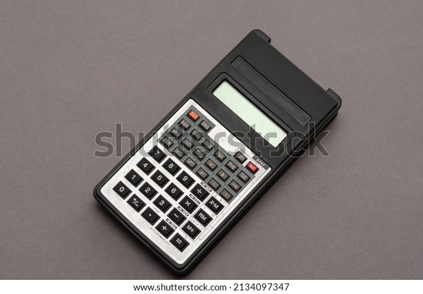 Scientific calculator against gray background.\
Rectangular device designed for engineering and scientific clock\
calculations. Selective\
focus.