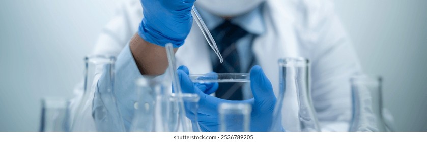 Scientist analyzing and dropping a sample into a glassware, experiments containing chemical liquid in laboratory on glassware - Powered by Shutterstock