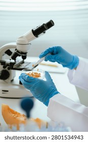 Scientist analyzing a fruit sample under a microscope in a food safety laboratory, performing quality control, nutritional assessment, and contamination testing of fresh produce.