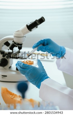 Scientist analyzing a fruit sample under a microscope in a food safety laboratory, performing quality control, nutritional assessment, and contamination testing of fresh produce.