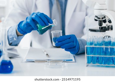 Scientist analyzing liquid in laboratory setting. Scientist is holding a conical flask with a blue liquid, conducting research in a laboratory equipped with a microscope and test tubes. - Powered by Shutterstock