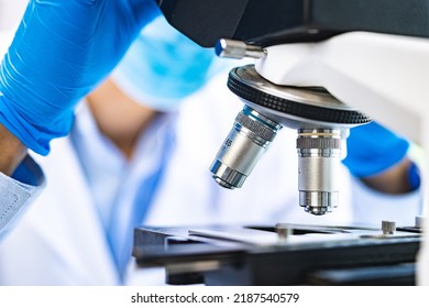 Scientist Analyzing Microscope Slide At Laboratory. Young Woman Technician Is Examining A Histological Sample, A Biopsy In The Laboratory Of Cancer Research