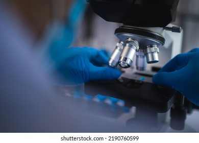 Scientist Analyzing Microscope Slide At Laboratory. Young Woman Technician Is Examining A Histological Sample, A Biopsy In The Laboratory Of Cancer Research