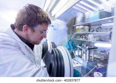 Scientist Assembling Lithium Ion Test Batteries In Glove Chamber In Battery Research Facility