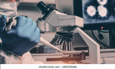 Scientist In Biohazard Protection Clothing Analyzing Covid 19 Sample With Microscope In Laboratory, Coronavirus Covid 19 Vaccine Research