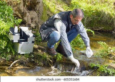 Scientist and biologist hydro-biologist takes water samples for analysis. / View of a Biologist take a sample in a river.