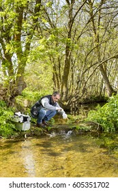 Scientist And Biologist Hydro-biologist Takes Water Samples For Analysis. / View Of A Biologist Take A Sample In A River.