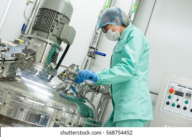 scientist in blue lab suit working with steel chromed tank with engine