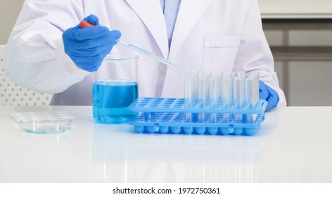 Scientist In Blue Shirt And Lab Coat Do Experiments In A Scientific Laboratory. Soft Focus Use For Background.