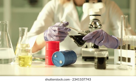 Scientist in chemical industrial laboratory holds black liquid crude oil in flask - Powered by Shutterstock