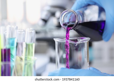 Scientist chemist pouring pink liquid into test tube in lab closeup - Powered by Shutterstock