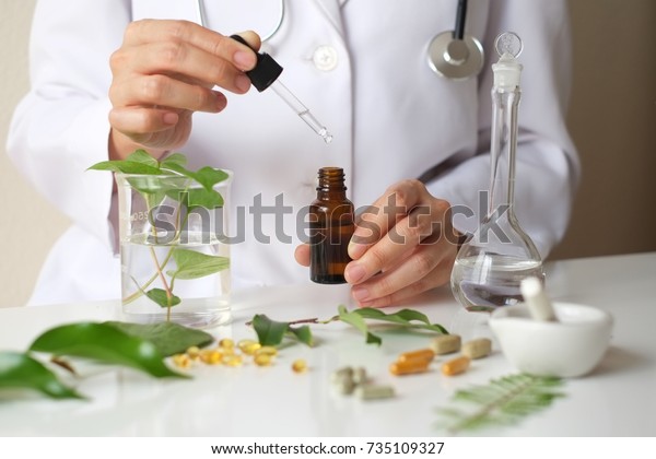 Scientist or doctor making alternative\
medicine herb , mortar, laboratory glassware, plant in tube, flower\
, on white\
background.