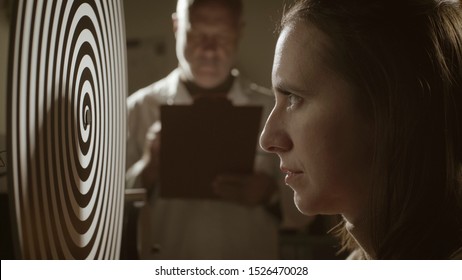 Scientist Doing Hypnosis Experiments In The Vintage Style Lab, A Woman Is Staring At The Rotating Spiral And Getting Hypnotized