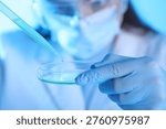 Scientist dripping liquid sample into Petri dish on light background, closeup