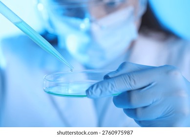 Scientist dripping liquid sample into Petri dish on light background, closeup