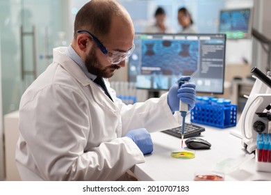 Scientist Dropping Blood Sample With Micropipette On Petri Dish In Genetic Laboratory. Team Of Researchers Examining Virus Evolution Using High Tech For Vaccine Development.