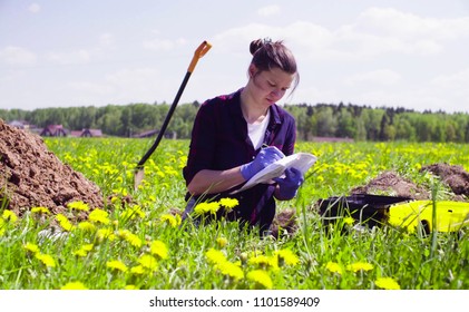 Scientist ecologist on the meadow writing something on the envelope.