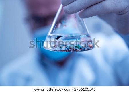 Scientist examining small plastic particles suspended in water in a laboratory flask