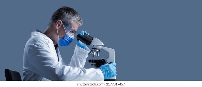 Scientist With Face Mask Examining A Sample Under The Microscope, Scientific Research Concept, Blank Copy Space