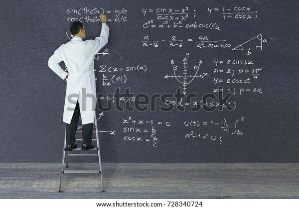 天才の科学者は 大きな黒板に白いチョークと複雑な数式を書くはしごの上に立っています の写真素材 今すぐ編集