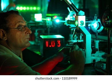 Scientist with glass demonstrate laser of microparticles near timer