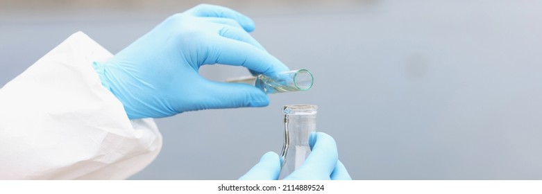 Scientist In Gloves And Protective Suit Pours Dirty Water From Test Tube Into Flask. Water Sampling Concept