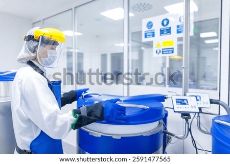Scientist Handling Cryogenic Storage in a High-Security Laboratory. A researcher wearing protective gloves, a face shield, and an insulated apron is carefully opening a liquid nitrogen storage tank.