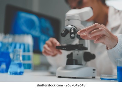 Scientist hands adjusting microscope controls for detailed sample analysis, with lab equipment and digital data in a research setting