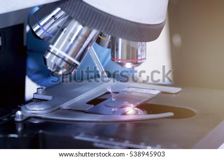 scientist hands using pipets drop oil to a microscope for Hematology blood test. 