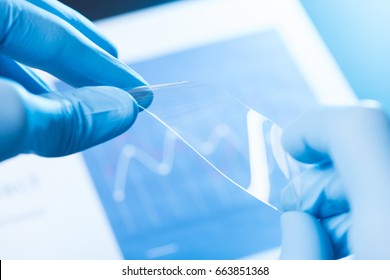 Scientist hold and bend in fingers small piece of transparent material, new type of material with different properties research concept - Powered by Shutterstock