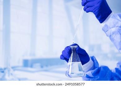 A scientist is holding a beaker filled with water. Concept of precision and focus, as the scientist carefully measures and pours the liquid. The blue color of the lab coat - Powered by Shutterstock