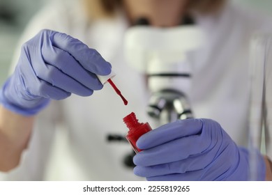 Scientist holding bottle with red paint and doing tests in laboratory. Science and lab research concept. - Shutterstock ID 2255819265