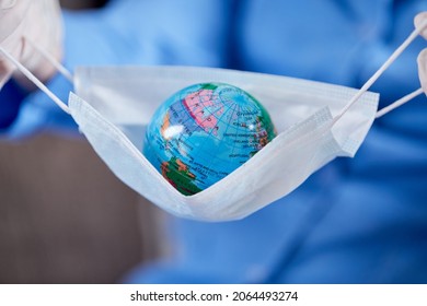 Scientist Holding Globe In Protective Mask