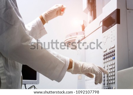 scientist holds an amber vial and press the control button of GC chromatography