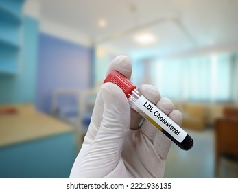 Scientist Holds Blood Sample For Ldl Cholesterol Test With Patient Bed Background.