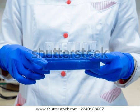 The scientist holds in front of him a tripod with small tubes of dna samples