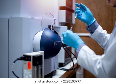 Scientist inject sample with micro syringe to TOF Mass Spectrometer for analysis in laboratory.