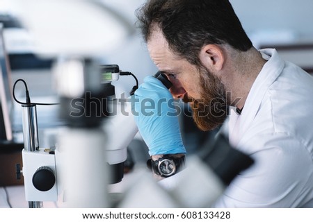 Scientist in laboratory looking through microscope
