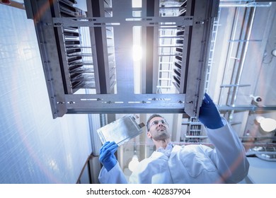 Scientist With Lithium Ion Pouch Cell Manufacture Machine In Battery Research Facility, Low Angle View