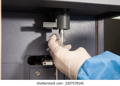Scientist loading a test tube containing a patient sample on the  flow cytometer for analysis. Flow cytometer